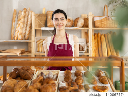 Young woman seller at showcase with pastries Young woman seller at showcase with pastries 140867574