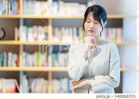 本棚の前に立つ困った表情の女性 作家 小説家 エッセイスト 本棚の前に立つ困った表情の女性 作家 小説家 エッセイスト 140868355