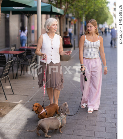 Senior woman and girl with pets walking in park 140868526