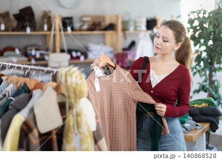Young woman chooses warm dress in clothing store Young woman chooses warm dress in clothing store 140868528