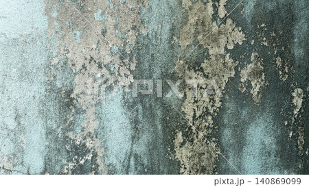 Showing a highly weathered and decaying plaster wall surface. Organic patches of white peeling paint grey mold and green moss form a rustic abstract pattern. 140869099
