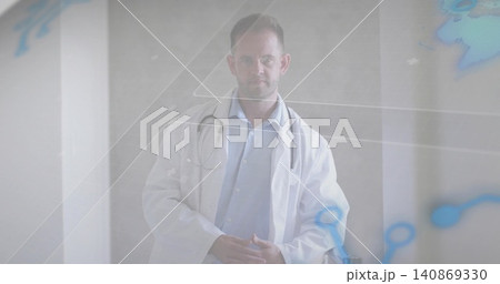 Standing male physician wearing lab coat and stethoscope in clinic portrait with molecular overlay 140869330