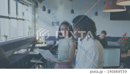 Talking woman wearing sleeveless top and headband presenting laptop and paper in coworking space 140869559