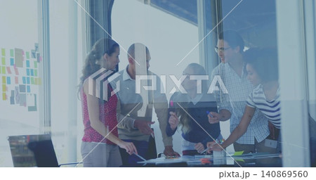 Leaning over conference table, five colleagues pointing at papers in glass room with sticky notes 140869560
