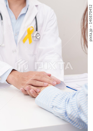 doctor holding patient hand to comfort and support with empathy for Yellow Ribbon concept of yellow September, Suicide prevention day, Childhood, July Sarcoma, bone and bladder cancer Awareness month doctor holding patient hand to comfort and support with empathy for Yellow Ribbon concept of yellow September, Suicide prevention day, Childhood, July Sarcoma, bone and bladder cancer Awareness month 140870452
