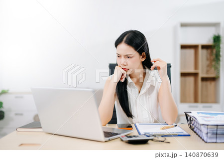 Focused businesswoman sorting documents at a cluttered desk with reports, coffee cups, and files. Perfect for accounting, finance, tax season, and deadline stress concepts. Focused businesswoman sorting documents at a cluttered desk with reports, coffee cups, and files. Perfect for accounting, finance, tax season, and deadline stress concepts. 140870639