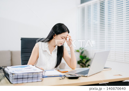 Focused businesswoman sorting documents at a cluttered desk with reports, coffee cups, and files. Perfect for accounting, finance, tax season, and deadline stress concepts. Focused businesswoman sorting documents at a cluttered desk with reports, coffee cups, and files. Perfect for accounting, finance, tax season, and deadline stress concepts. 140870640