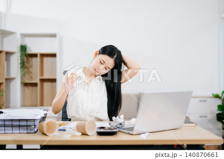 Young Asian woman suffering neck pain while working from home with laptop. Concept of stress, fatigue, burnout, workload and remote work challenges. 140870661