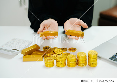 Gold coins and bars stacked beside laptop with market chart. Investment, finance, trading, profit growth, wealth strategy and business analysis concept. 140870773