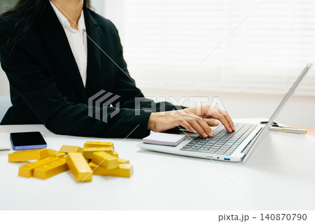 Professional working on laptop with gold bars on desk. Investment, finance, trading, wealth growth, market strategy and modern business concept. Professional working on laptop with gold bars on desk. Investment, finance, trading, wealth growth, market strategy and modern business concept. 140870790