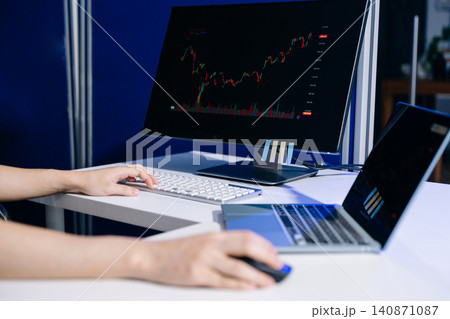 Focused trader reviewing financial charts and market data on multiple screens. Ideal for stock trading, investment, fintech, analytics, and business concepts. Focused trader reviewing financial charts and market data on multiple screens. Ideal for stock trading, investment, fintech, analytics, and business concepts. 140871087