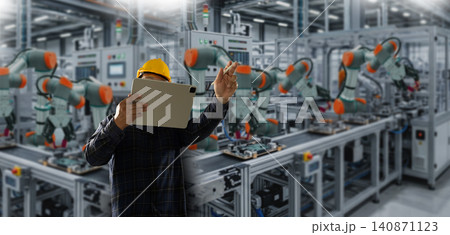 Engineers control wearing a safety helmet uses a tablet to monitor robotic arms on a factory production line, showing industrial automation control and manufacturing process workflow supervision. Engineers control wearing a safety helmet uses a tablet to monitor robotic arms on a factory production line, showing industrial automation control and manufacturing process workflow supervision. 140871123