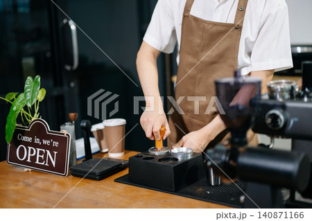 Professional cafe owner preparing coffee in a modern coffee shop with espresso machine and digital tablet, showcasing small business lifestyle Professional cafe owner preparing coffee in a modern coffee shop with espresso machine and digital tablet, showcasing small business lifestyle 140871166