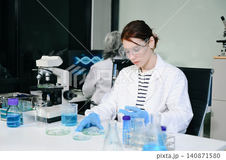 Two scientist or medical technician working, having a medical discuss meeting with an Asian senior female scientist supervisor in the laboratory with online reading, test samples and innovation Two scientist or medical technician working, having a medical discuss meeting with an Asian senior female scientist supervisor in the laboratory with online reading, test samples and innovation 140871580