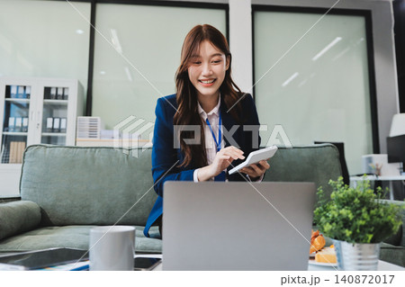 Asian businesswoman sitting at work using laptop talking and consulting in office Asian businesswoman sitting at work using laptop talking and consulting in office 140872017