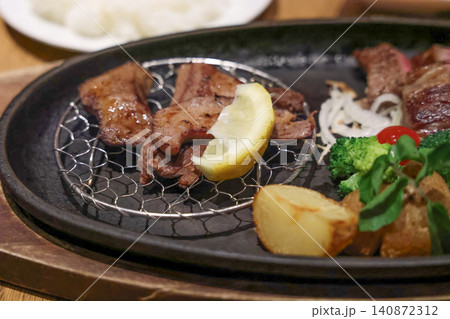 Grilled beef slices on hot plate with vegetables and lemon Grilled beef slices on hot plate with vegetables and lemon 140872312