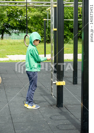 Child exploring calisthenics workout ground with gymnastic rings and bars Child exploring calisthenics workout ground with gymnastic rings and bars 140873451