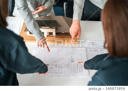 住宅模型,設計図を指差すビジネスマンの手元 住宅模型,設計図を指差すビジネスマンの手元 140873959