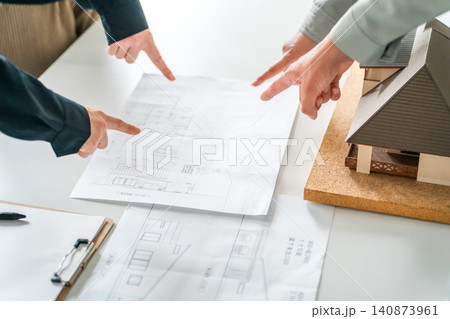 住宅模型,設計図を指差すビジネスマンの手元 住宅模型,設計図を指差すビジネスマンの手元 140873961