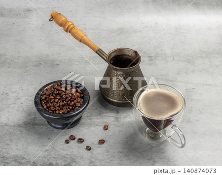 Stone bowl with roasted coffee beans, a cup of coffee and a cezve. 140874073