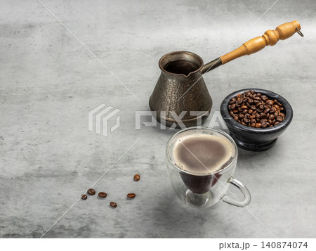 Cup of coffee, a stone bowl with roasted coffee beans and a cezve. 140874074