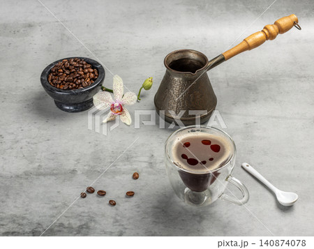 Cup of coffee, a stone bowl with roasted coffee beans and a cezve. Cup of coffee, a stone bowl with roasted coffee beans and a cezve. 140874078