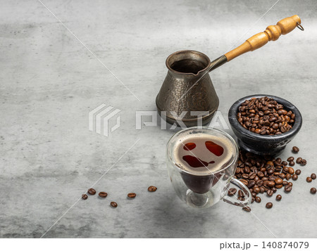 Cup of coffee, a stone bowl with roasted coffee beans and a cezve. Cup of coffee, a stone bowl with roasted coffee beans and a cezve. 140874079