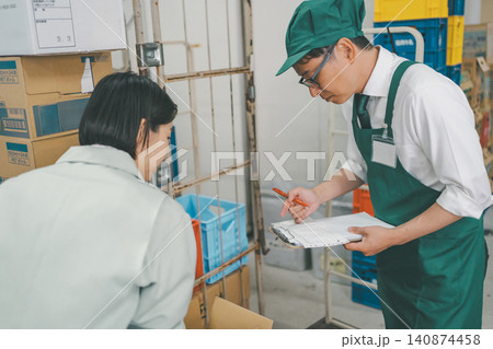 バックヤードでクリップボードに荷受け内容を書き込む男性スタッフ バックヤードでクリップボードに荷受け内容を書き込む男性スタッフ 140874458