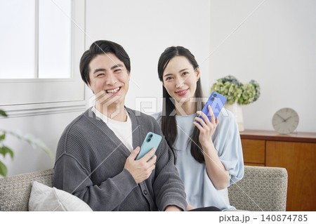 リビングでスマホを持っているカップルのポートレート カメラ目線 リビングでスマホを持っているカップルのポートレート カメラ目線 140874785