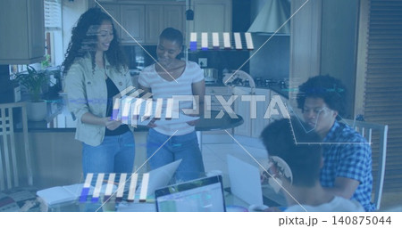 Reviewing papers, four people in jeans at home kitchen island using laptops and overlays 140875044