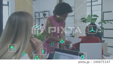 Leaning woman in pink dress showing paper to colleague in red turtleneck at desk, plants icons 140875147