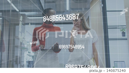 Walking two women in glass office hall, workwear, checking silver laptop, yellow file, AR overlay Walking two women in glass office hall, workwear, checking silver laptop, yellow file, AR overlay 140875240