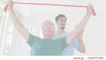 Raising senior in green tee pulling red band up in clinic, assistant in light-blue scrubs guiding Raising senior in green tee pulling red band up in clinic, assistant in light-blue scrubs guiding 140875388