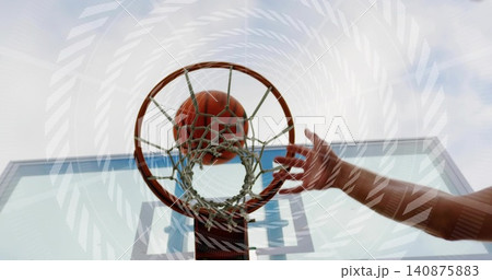 Swooshing basketball passing through rim at outdoor court, bare arm reaching toward glass backboard 140875883