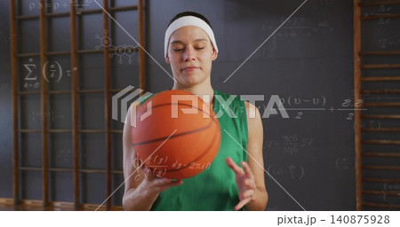 Holding woman green jersey white headband gripping orange basketball gym wooden bars math wall Holding woman green jersey white headband gripping orange basketball gym wooden bars math wall 140875928