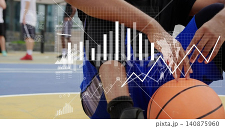 Crouching athlete holding orange basketball at painted court in black top blue shorts with charts Crouching athlete holding orange basketball at painted court in black top blue shorts with charts 140875960