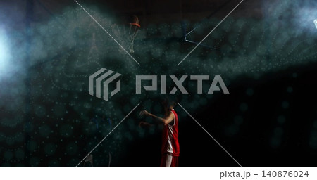 Shooting basketball player wearing red-and-white finishing in spotlit gym haze, basketball near rim 140876024