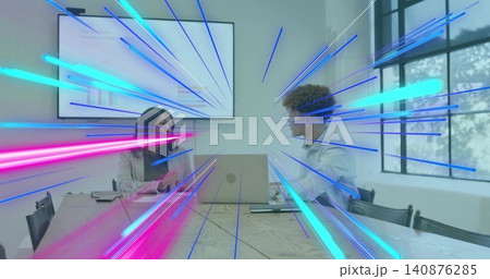Talking coworkers wearing light blazers reviewing slide while using laptop in meeting, neon rays 140876285