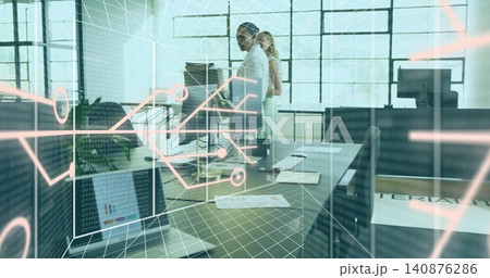 Reviewing code, two colleagues in business casual at open office, with laptop, monitors, AR overlay 140876286