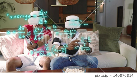 Playing two adults wearing red and striped tops, VR headsets, holding gamepads on sofa with popcorn 140876814