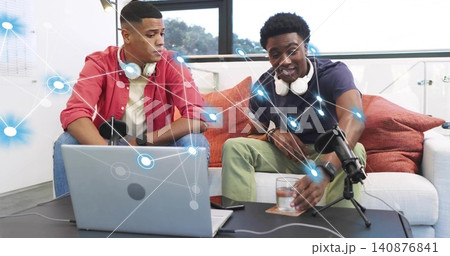 Recording two men in red shirt and navy polo speaking into microphone in living-room studio, laptop Recording two men in red shirt and navy polo speaking into microphone in living-room studio, laptop 140876841