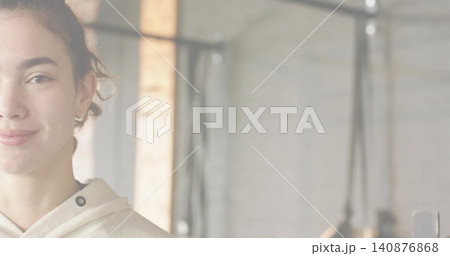 Smiling adult female wearing light hoodie standing at gym with rig, ropes, brick column, copy space Smiling adult female wearing light hoodie standing at gym with rig, ropes, brick column, copy space 140876868
