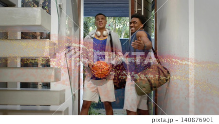 Standing two men holding basketball, carrying duffel in entryway, wearing hoodie and sleeveless top Standing two men holding basketball, carrying duffel in entryway, wearing hoodie and sleeveless top 140876901