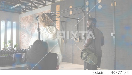 Walking partners carrying backpack and green duffel into fitness studio in hoodie and dark tee 140877189
