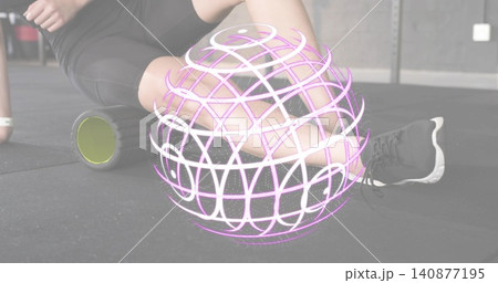 Foam-rolling female targeting IT-band in gym, in black shorts, on green roller with wireframe globe Foam-rolling female targeting IT-band in gym, in black shorts, on green roller with wireframe globe 140877195