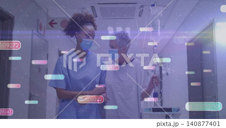 Walking nurse in blue scrubs supporting patient in hospital hall holding IV pump masks digital tags Walking nurse in blue scrubs supporting patient in hospital hall holding IV pump masks digital tags 140877401