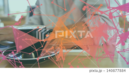 Showing black cup wood-saucertable in cafe man-light-shirt typing on pc near device pink-orange net Showing black cup wood-saucertable in cafe man-light-shirt typing on pc near device pink-orange net 140877884
