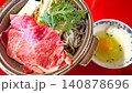 赤いテーブルの上に置かれた霜降り牛肉と生卵付きのすき焼き鍋 140878696