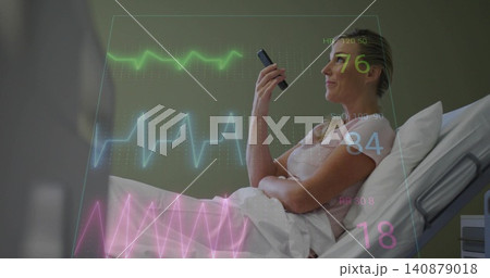 Reclining patient in hospital bed in short-sleeve top, holding device and looking upward with ECG Reclining patient in hospital bed in short-sleeve top, holding device and looking upward with ECG 140879018