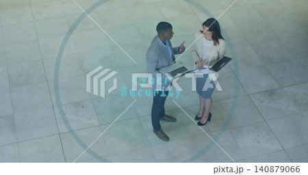 Discussing colleagues in blazers holding laptop and folder at corporate atrium, Cyber Security text 140879066